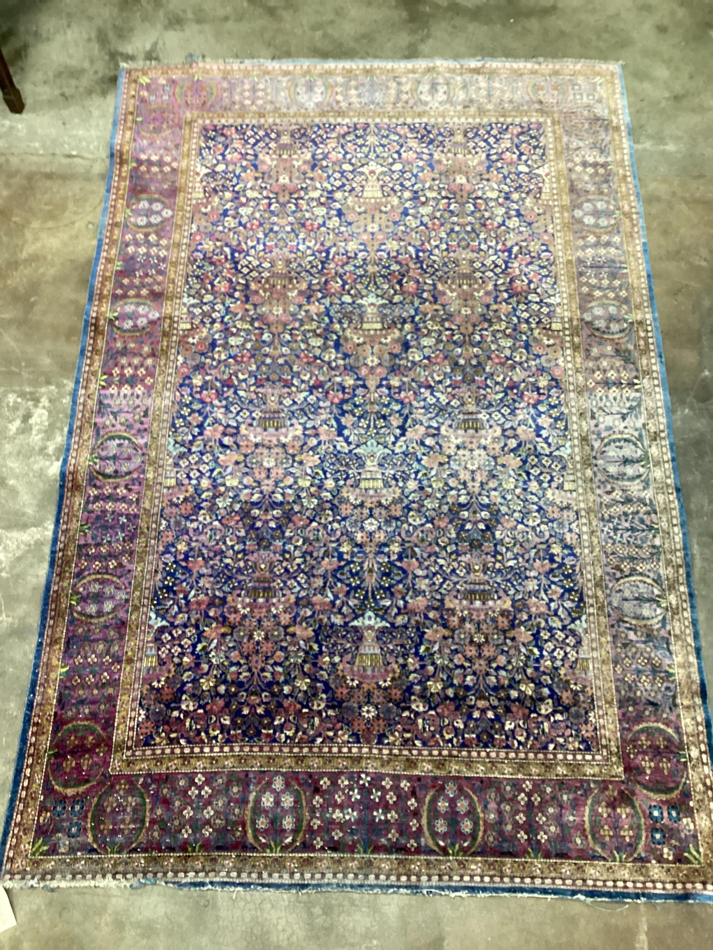 A Tabriz part silk blue ground rug with central field of flowers in urns, 200 x 128cm (a.f.)